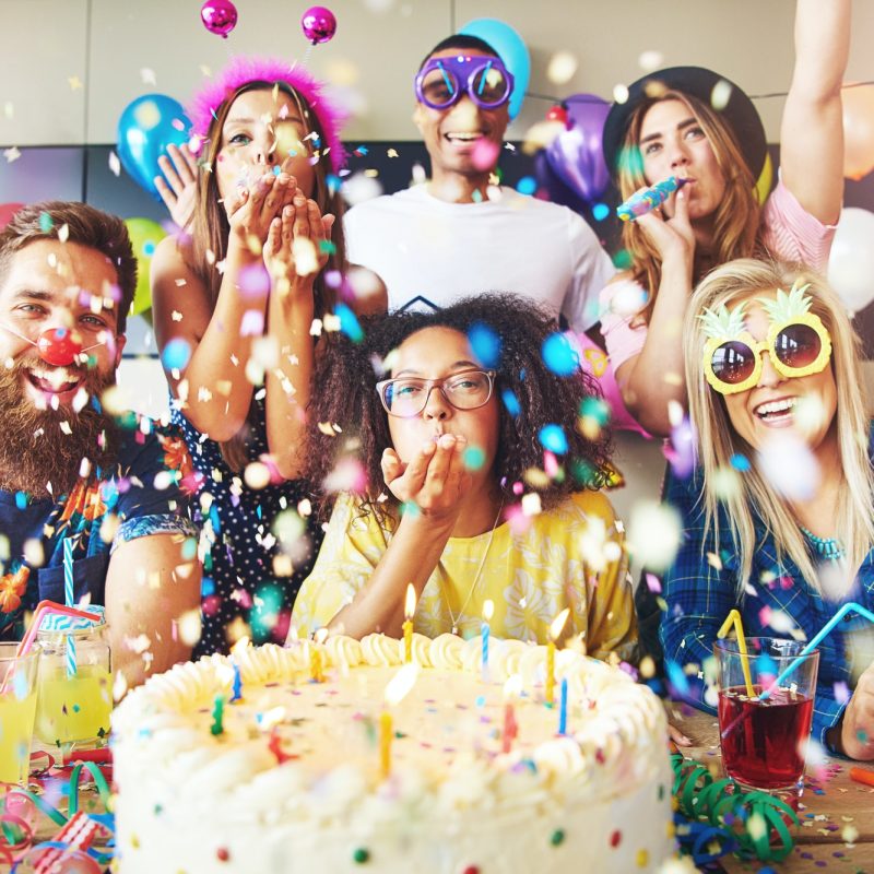 confetti-flying-around-group-celebrating-a-party.jpg birthday party package celebration in dubai with people enjoying a cake